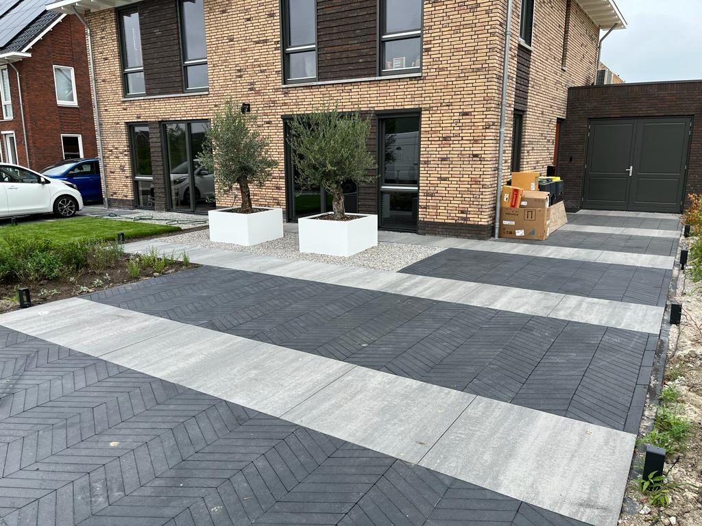 Oprit en voortuin met banen visgraatklinkers en lichte tegels bij een moderne woning